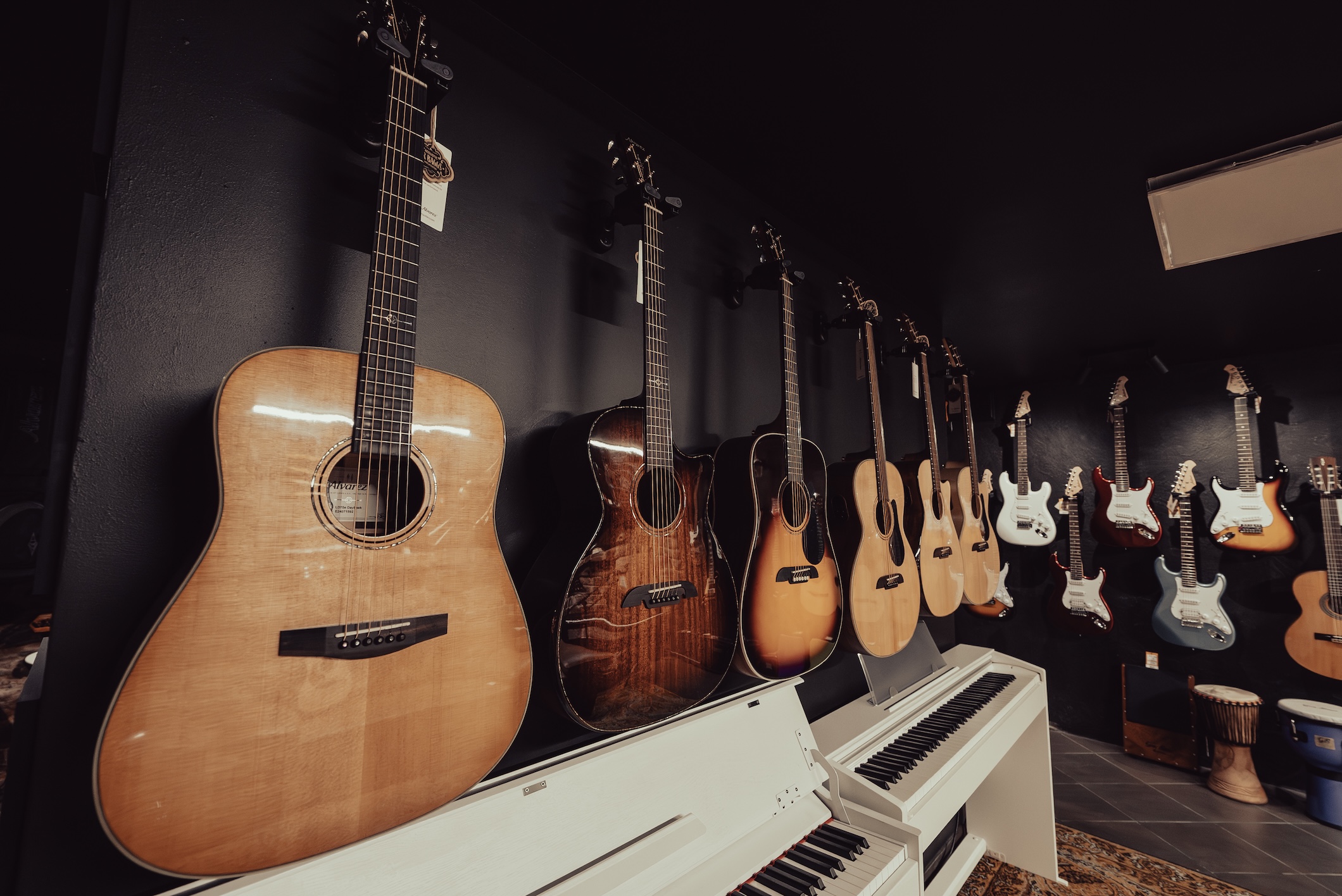 Gitara akustyczna w Brumi Toruń – ściana instrumentów w różnych kształtach pudła i wykończeniach, możliwość cichego i głośnego testowania w salce.